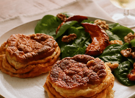 Zwei Käse-Soufflés mit einem Salat und einem Glas Wein.