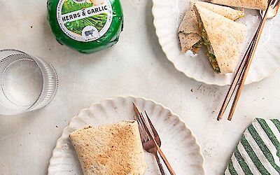 Wrap with chicken, pesto, cheese, and garlic served on two plates.