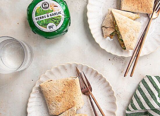 Wrap mit Hähnchen, Pesto, Käse und Knoblauch, serviert auf zwei Tellern.