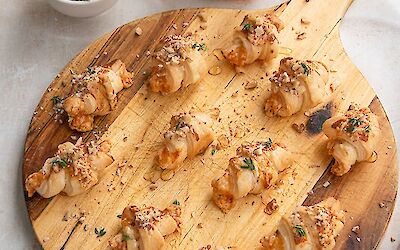 12 mini croissants on a round wooden board.