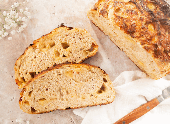 Artisan cheese bread with Jersey cheese, sliced, showing an airy crumb and golden brown crust on a light surface.